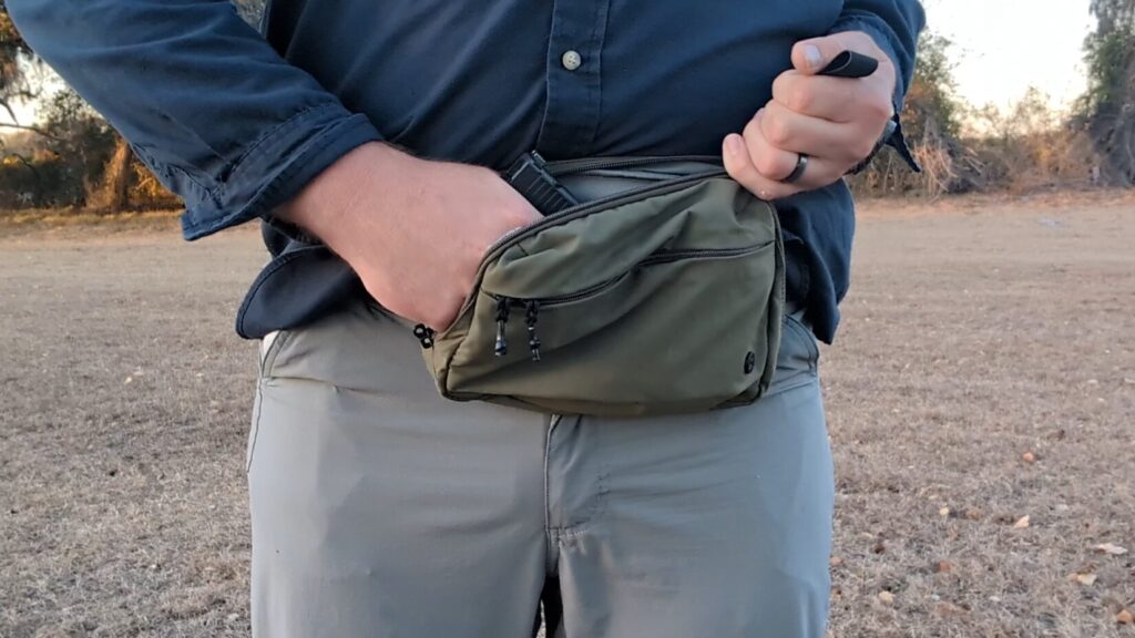 A hand reaching into an open tactical bag to demonstrate the fit of a holstered Glock pistol.
