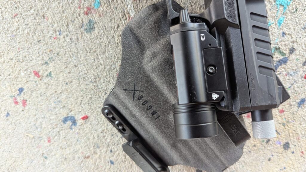 A tight shot of the Streamlight TLR-1 mounted on the Echelon, partially inserted into the holster to show the light-bearing fitment.