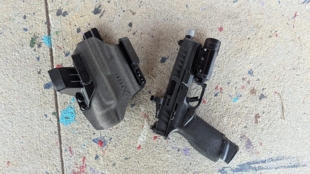 The Echelon pistol with a weapon light and threaded barrel laid next to the empty IncogX holster on a concrete floor
