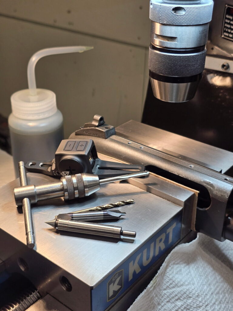 A shotgun receiver in a gunsmiths vice. drilled and tapped to install a red dot sight