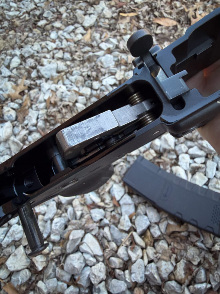 A disassembled AR-15 receiver on a gravel background