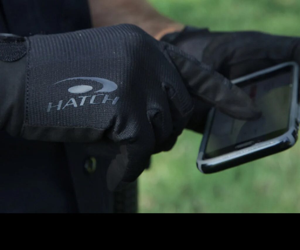 image of hand wearing hatch duty glove touching the screen of a small electronic device.