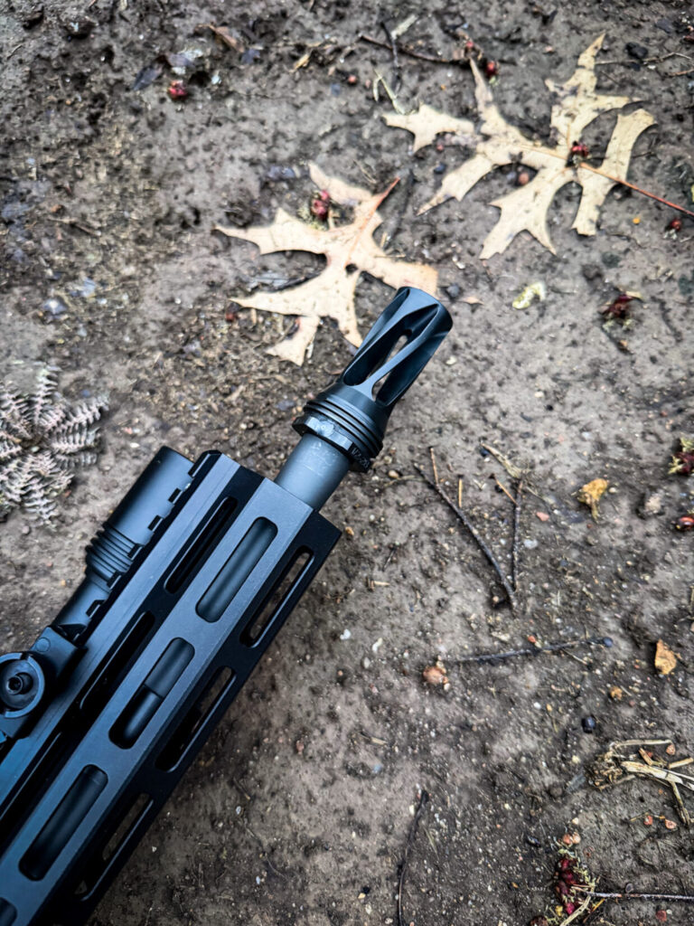 black rifle with a HUXWRX flash hider on a brown background