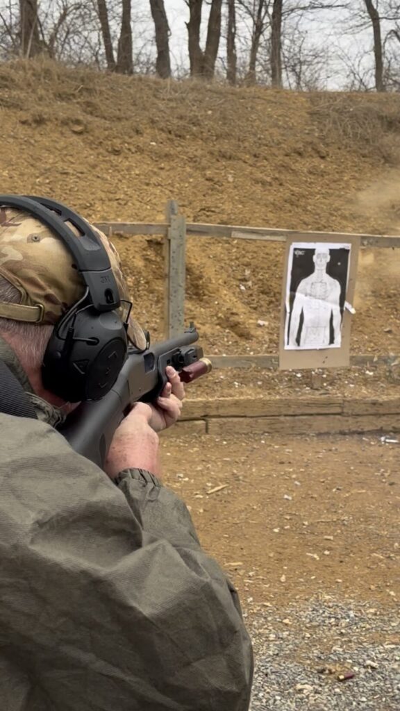 shooter firing a combat shotgun on the range during a training exercise. a red shotgun shell is being ejected