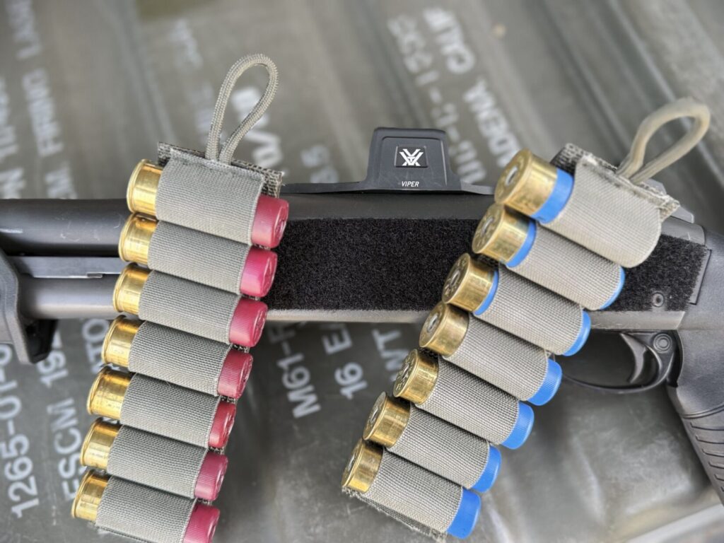 a side profile of a shotgun receiver covered in velcro. 2 7 round shotgun cards are propped against the receiver.