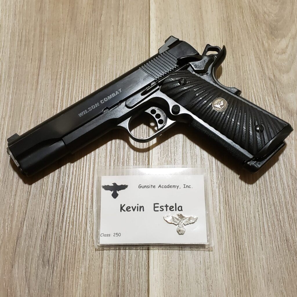 A 1911 pistol and name badge against a wooden background.