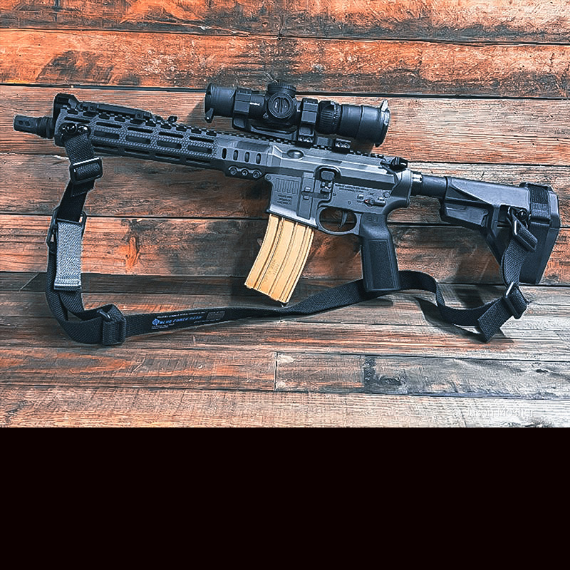 The Mk1 rifle with the Vickers sling attached to it, leaning up against a wood wall. 