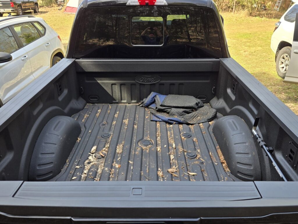 The bed of a pickup truck parked next to other vehicles