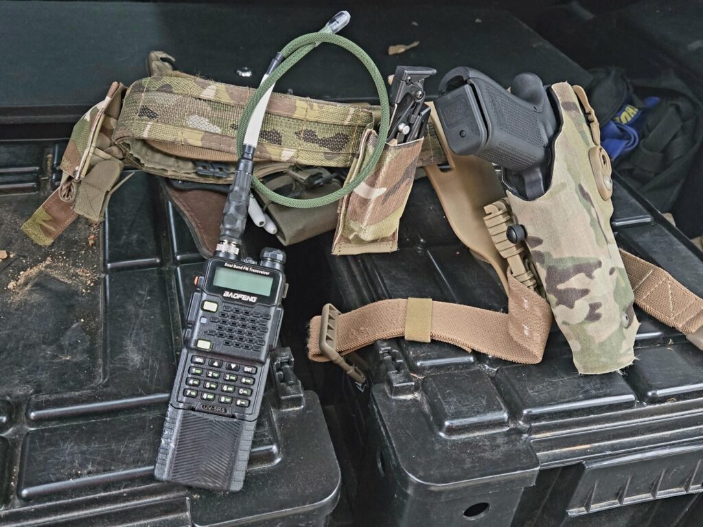 Two way radio and a multicam pistol belt on top of cargo boxes