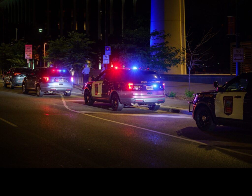 police cars with lights on, side of city road at night