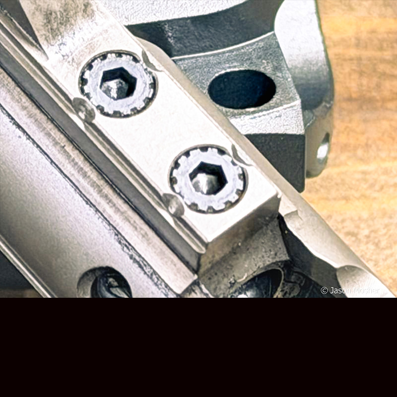 A view of the top of a gas key, showing two screws and the metal pushed against them after being staked. 