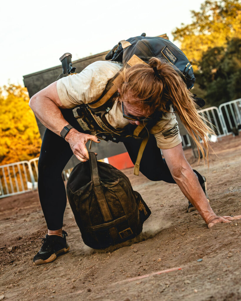 A woman in tactical kit dragging a weighted sand bag.