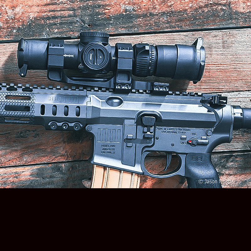 A side view of the Vortex AMG LPVO optic mounted to the MK1 rifle, leaning up against a wooden wall. 