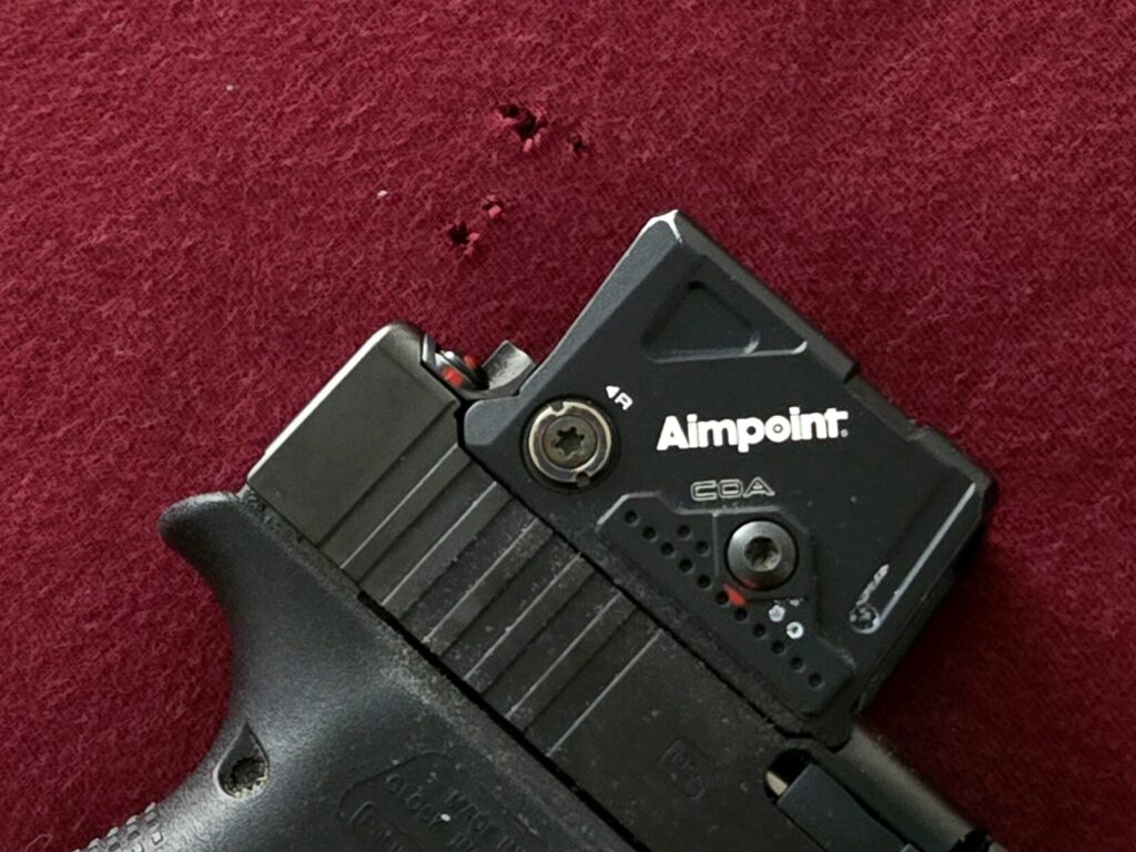 Holes in a shirt and a firearm with wear to the optic