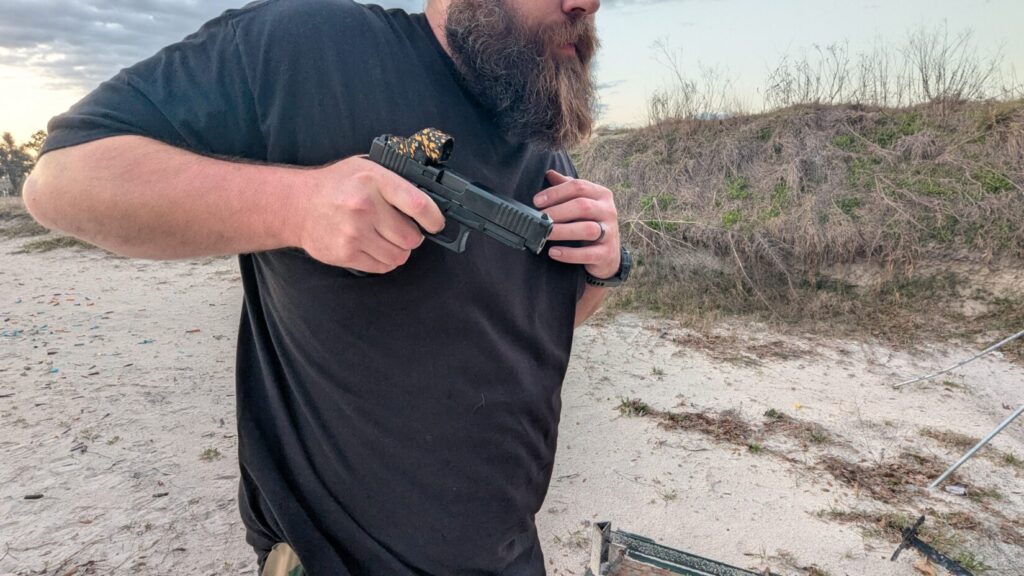 A side profile of a shooter demonstrating a retention draw, with the handgun held close to the body and the elbow tucked back to prevent an attacker from grabbing the gun.