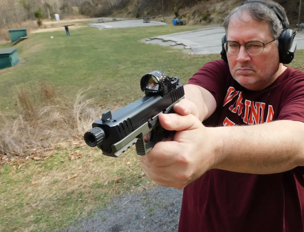 Man shooting a pistol with a red dot optic
