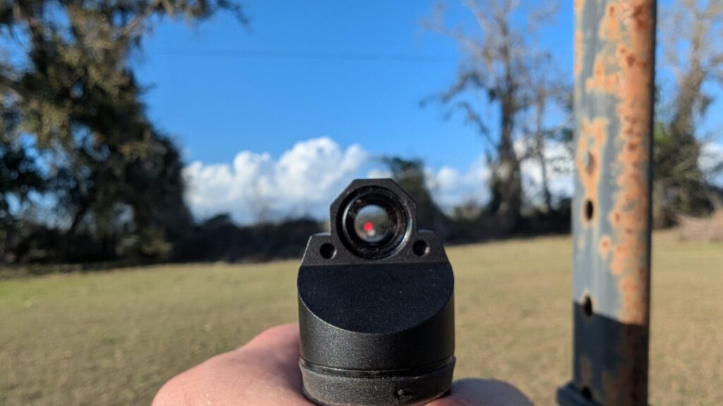 A clear "sight picture" view through the Leupold DeltaPoint Micro optic, showing the illuminated red dot centered on a field background.