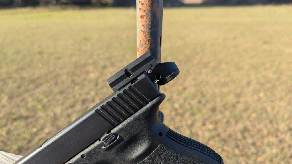 A close-up side view of the Leupold DeltaPoint Micro mounted on a Glock slide, showing the unique direct-to-rear-sight dovetail mounting system.