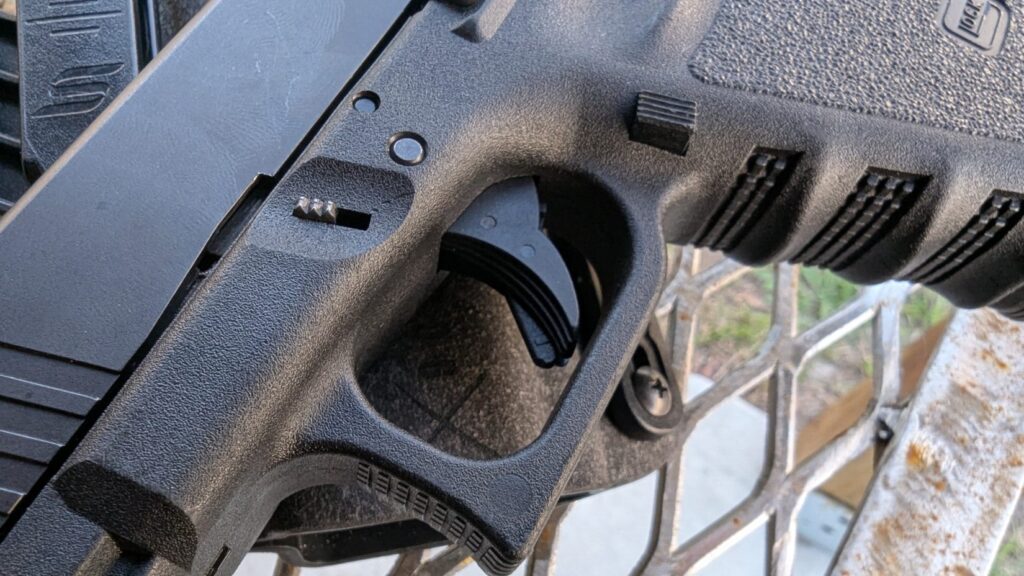Extreme close-up of a Glock trigger and magazine release, showing the mechanical safety features.