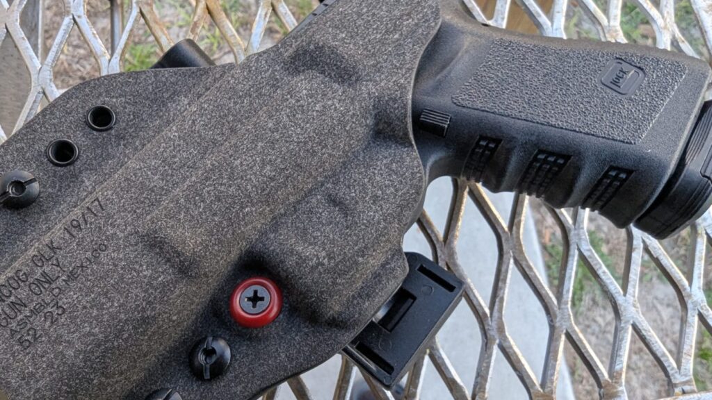 Close-up of a Glock 19/17 seated in a gray patterned Kydex holster, highlighting the trigger guard protection.