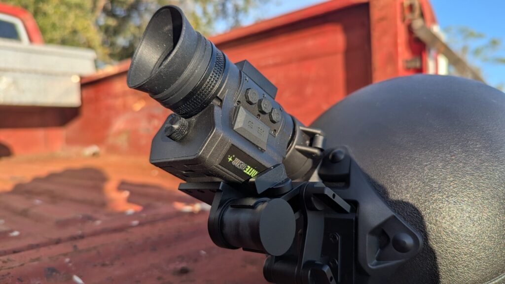 The NVG 50 flipped up into the stowed position on a tactical helmet, showing the underside of the mounting arm and the device's compact profile.
