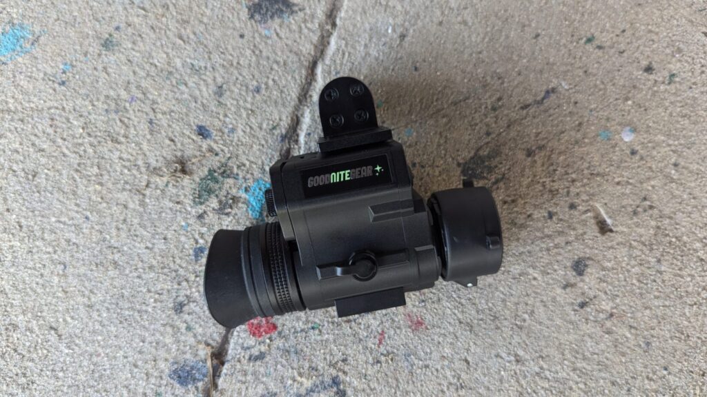 A top-down look at the NVG 50 resting on a concrete surface, showing the dovetail mounting plate and the eyepiece's rubber cup.