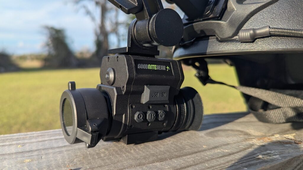 Profile view of the NVG 50 mounted to a tactical helmet via a Wilcox-style flip-up mount, showing the device in the "down" position.