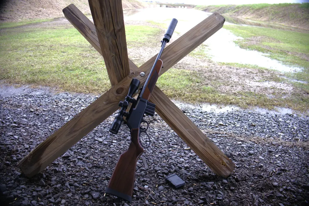 Henry Lever Action Supreme Rifle, equipped with a scope and a suppressor, leaning upright