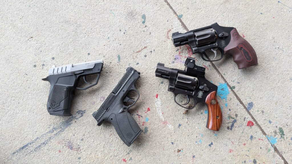 A group shot of four compact firearms: a Taurus, a S&W Bodyguard 2.0, and two snub-nosed revolvers, showcasing various carry configurations.