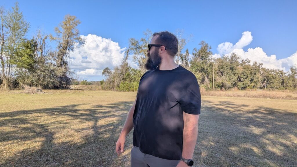 A man in a black t-shirt looking sharply to his right, demonstrating "scanning" behavior to check for witnesses or escape routes.