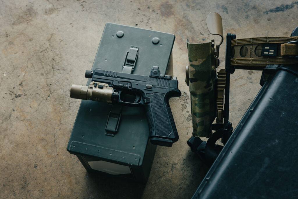 Ruger RXM in Mischief Machine Grip frame with a Surefire X300 weapon light and an RMR optic. sitting on an ammo can next to a Safariland holster