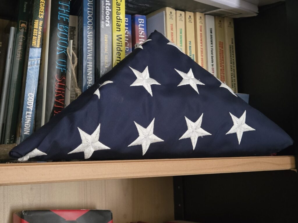 A folded American flag on a book shelf