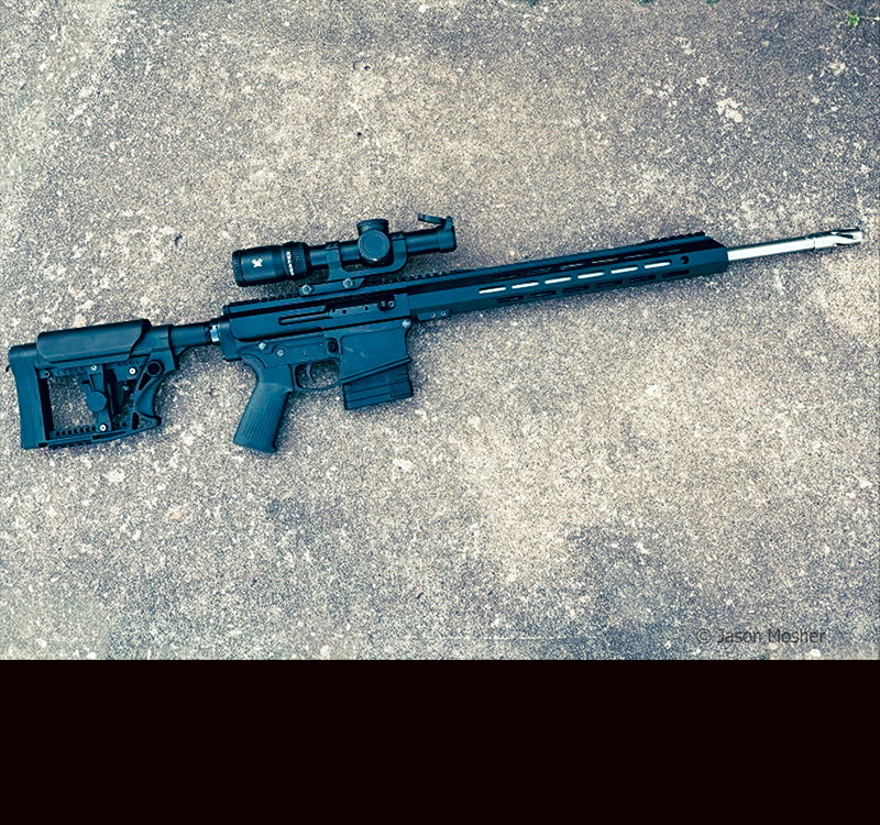 A black rifle, laying on concrete.