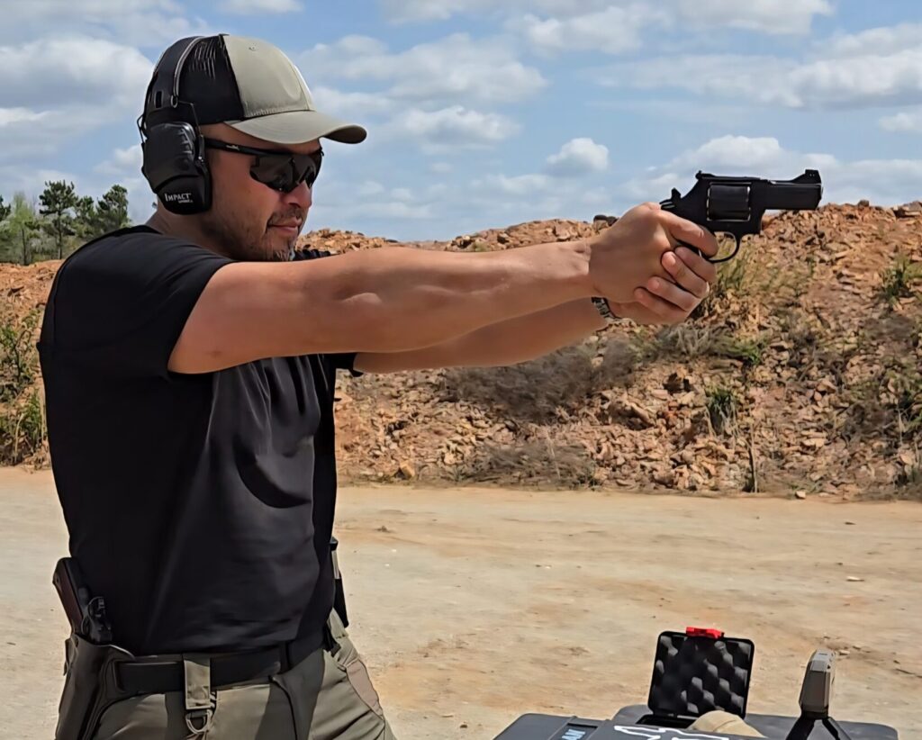 A man in a black shirt shooting a revolver