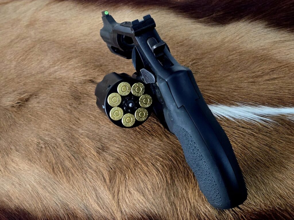A revolver with the cylinder open on top of an African game animal hide.