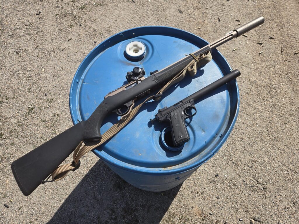 A rifle and a pistol on top of a range barrel
