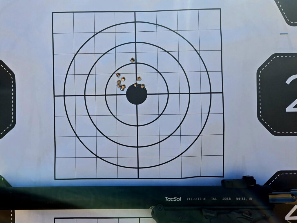 A target with 10 holes in it and a pistol held in the lower third of the photo