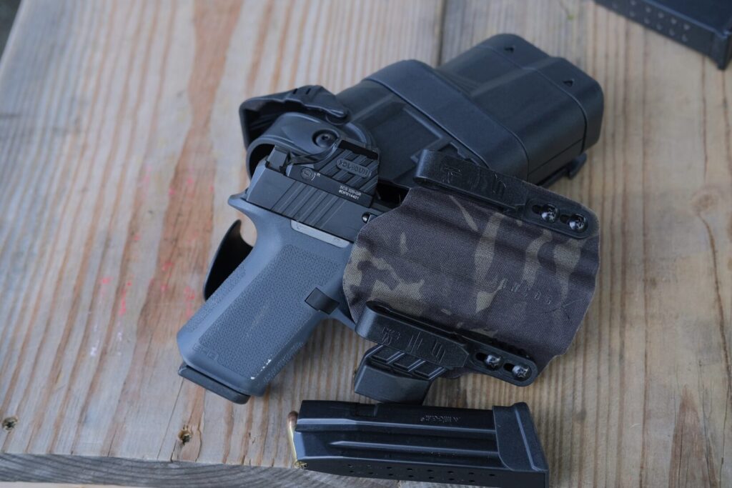 RXM with the mid sized grey grip frame, and a Holosun SCS320 in an Icog X holster, propped up by a Safariland Ballast Holster and next to a Mec Gar 18 round G19 magazine
