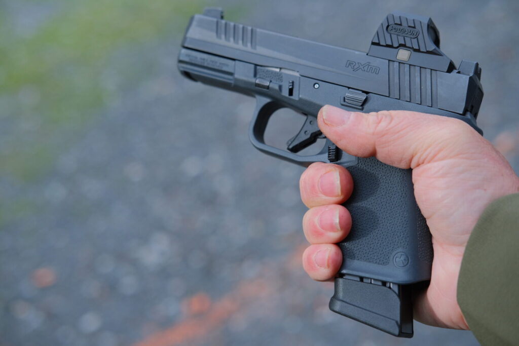 Side profile view of the Ruger RXM in hand with a grey, mid-sized grip frame and Mec Gar 18 round magazine installed.