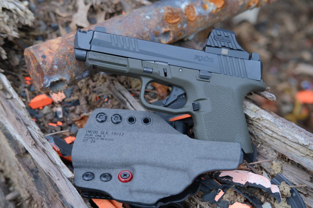 Ruger RXM with Holosun SCS320 and an installed Radian Ramjet and Afterburner, slide closed on a green subcompact frame and the back side of a Safariland Incog X holster in the foreground.
