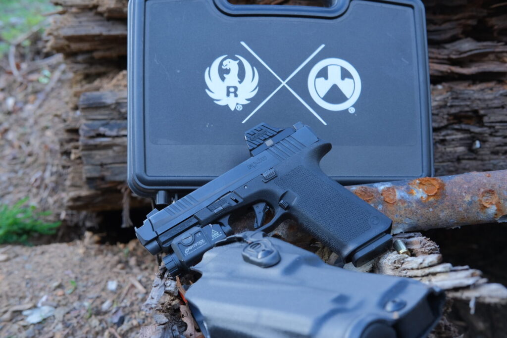 a Ruger RXM pistol with a holster in the foreground and a pistol case in the background