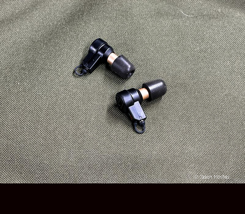 A pair of black ear buds laying on a gray surface.