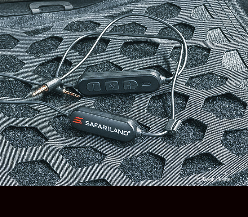 A black lanyard for ear buds laying on a black tactical bag.