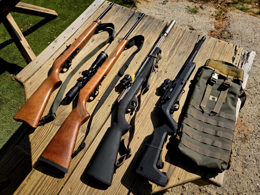 Rifles on a wooden shooting bench along with a take-down rifle case.