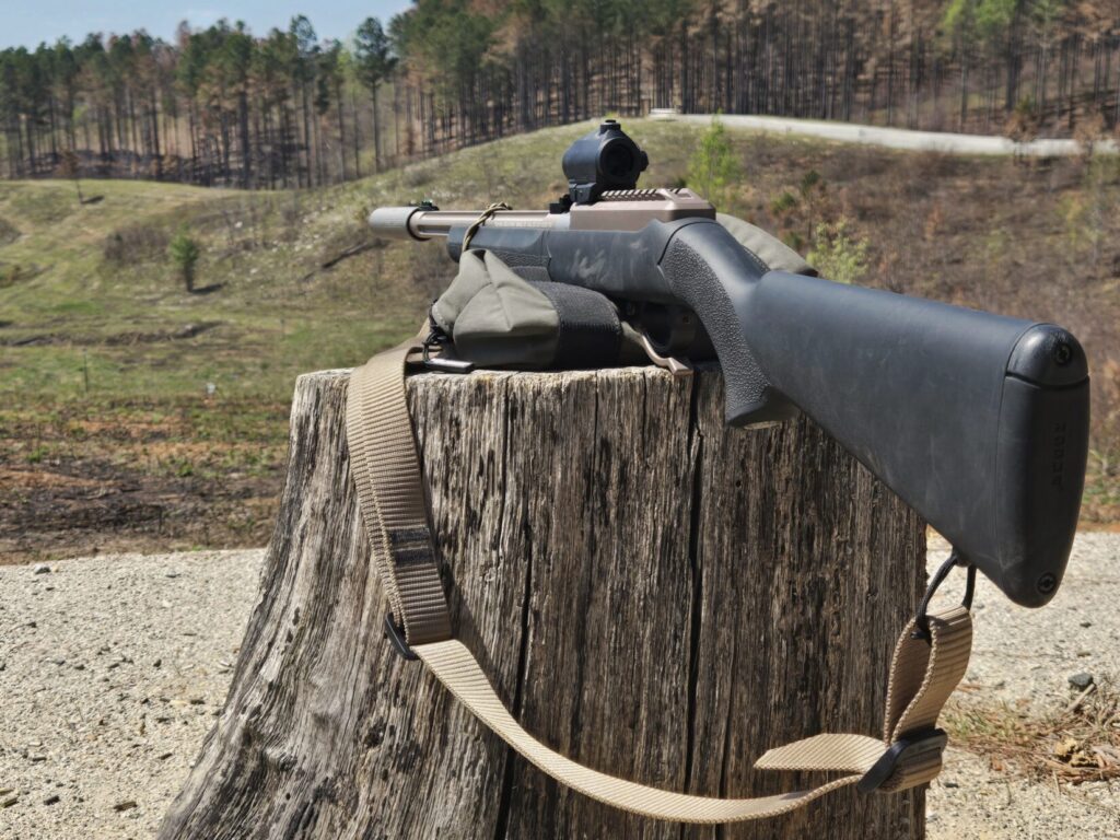 A rifle on a wooden stump aimed down range