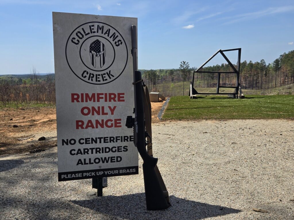 A rifle leaning up against a sign at a rifle range