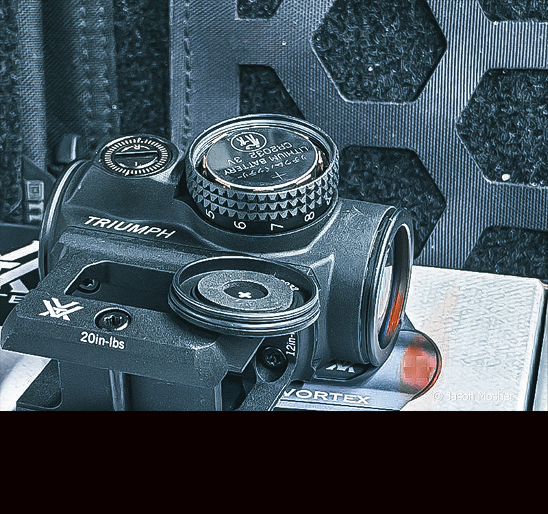 The Triumph optic with the battery cap off, exposing the battery underneath. 