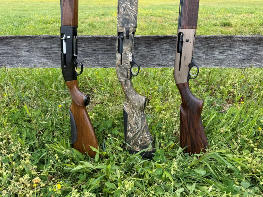 Beretta AL-2, A300 Ultimate, and A400 XPLOR shotguns leaning against a rail fence