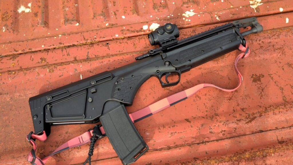 The KelTec RDB-S with a red and black sling resting on the bed of a red pickup truck.