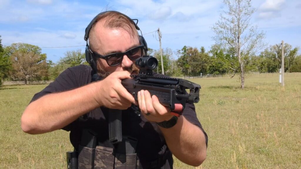 A close-up profile of a shooter aiming the RDB-S, emphasizing the rifle's short overall length.